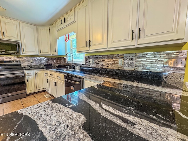 kitchen featuring a sink, dark stone countertops, tasteful backsplash, appliances with stainless steel finishes, and light tile patterned floors