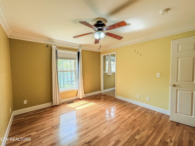 unfurnished room with visible vents, light wood-style floors, ceiling fan, and crown molding