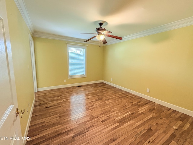 empty room with baseboards, wood finished floors, ceiling fan, and crown molding
