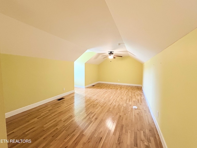 additional living space with light wood-style floors, vaulted ceiling, visible vents, and baseboards