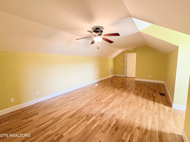 additional living space with lofted ceiling, visible vents, a ceiling fan, baseboards, and light wood-style flooring
