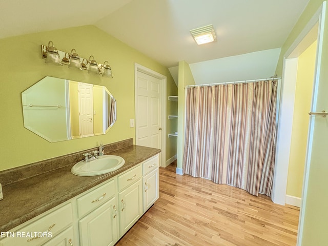 bathroom with vaulted ceiling, a shower with curtain, vanity, and wood finished floors