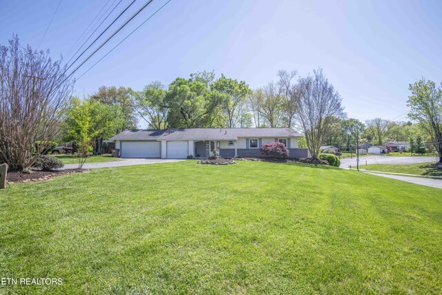 ranch-style home featuring a front lawn, a garage, and driveway