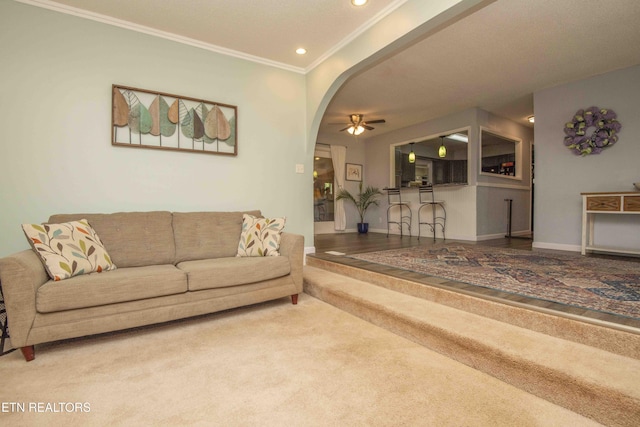 carpeted living area featuring crown molding, ceiling fan, arched walkways, recessed lighting, and baseboards