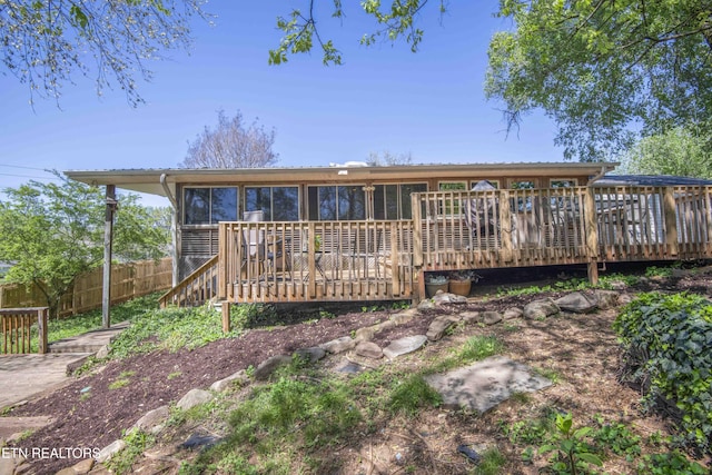 back of property with a deck and fence