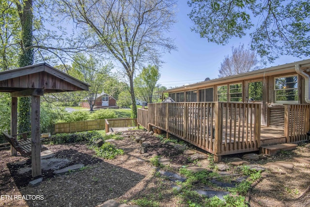 view of yard with fence, a wooden deck, and a sunroom