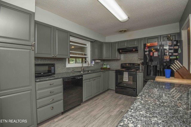 kitchen featuring a sink, a textured ceiling, under cabinet range hood, black appliances, and gray cabinetry