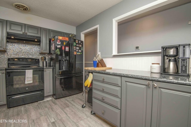 kitchen featuring visible vents, black appliances, under cabinet range hood, decorative backsplash, and gray cabinetry