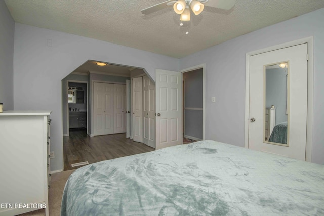 bedroom with visible vents, baseboards, a ceiling fan, a textured ceiling, and wood finished floors