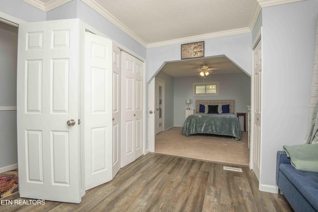 bedroom with crown molding, dark wood-style floors, and visible vents