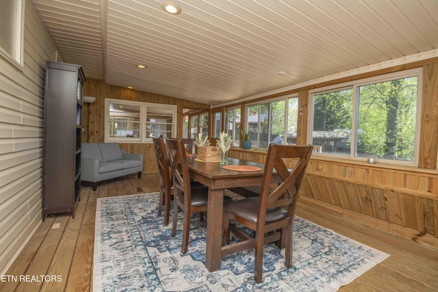 sunroom / solarium featuring vaulted ceiling, wooden ceiling, wood walls, wood-type flooring, and a deck