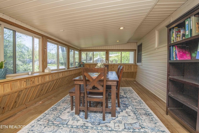 sunroom / solarium with wood-type flooring, wooden walls, lofted ceiling, a deck, and wood ceiling