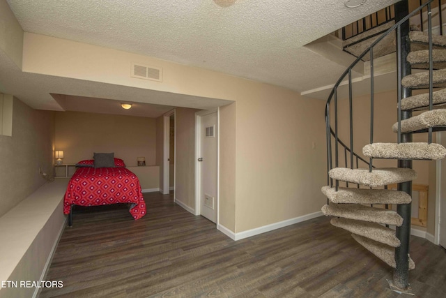 bedroom featuring a textured ceiling, wood finished floors, and visible vents