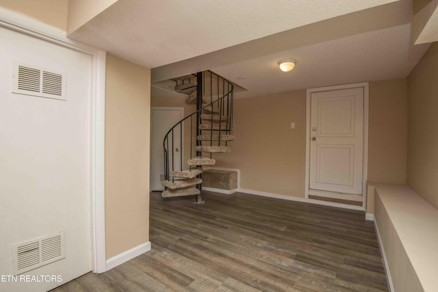 interior space featuring wood finished floors, baseboards, visible vents, and stairs