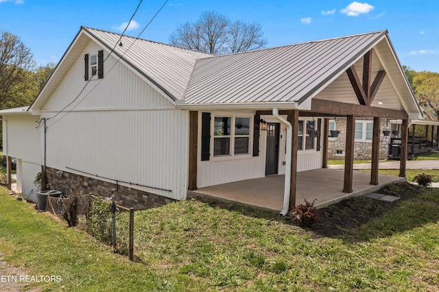 613 N St, Newport, TN 37821 - back of property featuring a standing seam roof, stone siding, metal roof, a lawn, and a patio