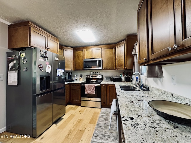 155 Oak Tree Ln, Sneedville, TN 37869 - kitchen featuring stainless steel appliances, light wood-style flooring, a sink, a textured ceiling, and light stone counters