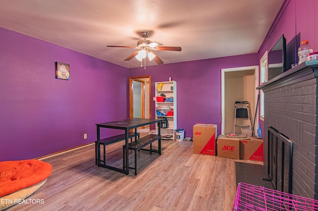 office space featuring wood finished floors, a fireplace, and a ceiling fan
