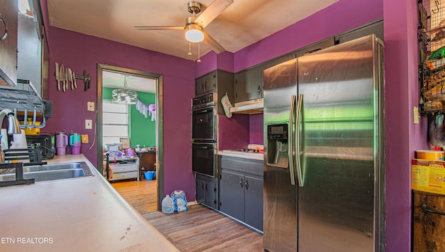 kitchen featuring light wood-style flooring, light countertops, a ceiling fan, stainless steel refrigerator with ice dispenser, and dobule oven black