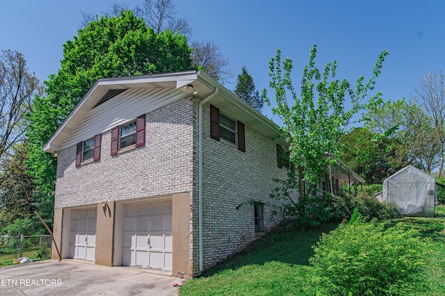 view of home's exterior with concrete driveway, an attached garage, an exterior structure, brick siding, and fence