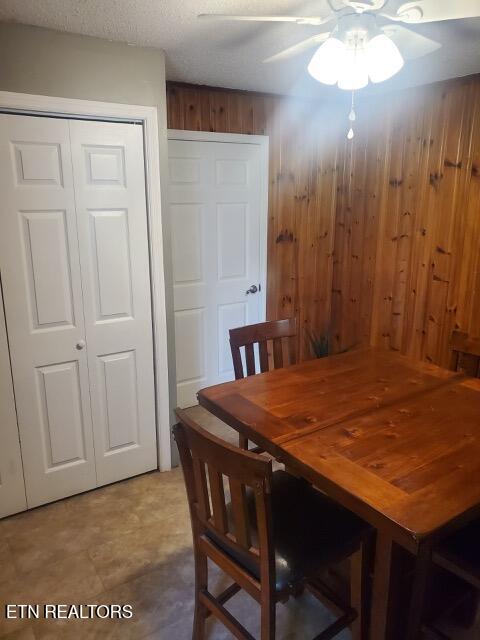 dining space with wood walls and ceiling fan