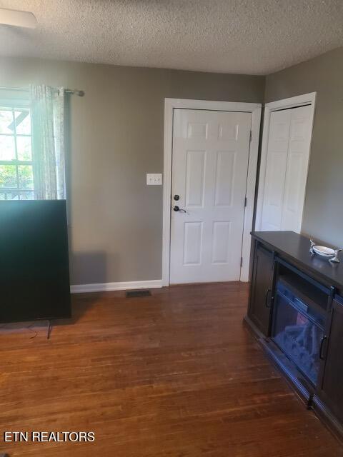 foyer with a textured ceiling, wood finished floors, baseboards, and visible vents