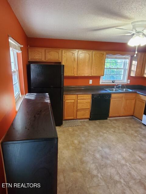kitchen with ceiling fan, a textured ceiling, black appliances, a sink, and dark countertops