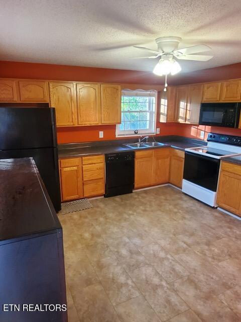 kitchen with ceiling fan, a sink, black appliances, and dark countertops