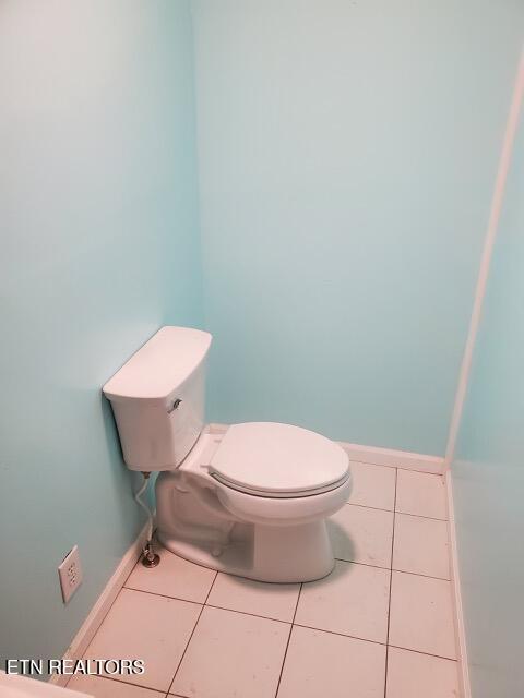 bathroom with toilet, tile patterned flooring, and baseboards