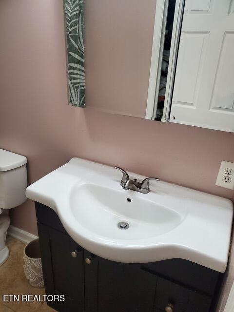 bathroom featuring toilet, tile patterned floors, vanity, and baseboards