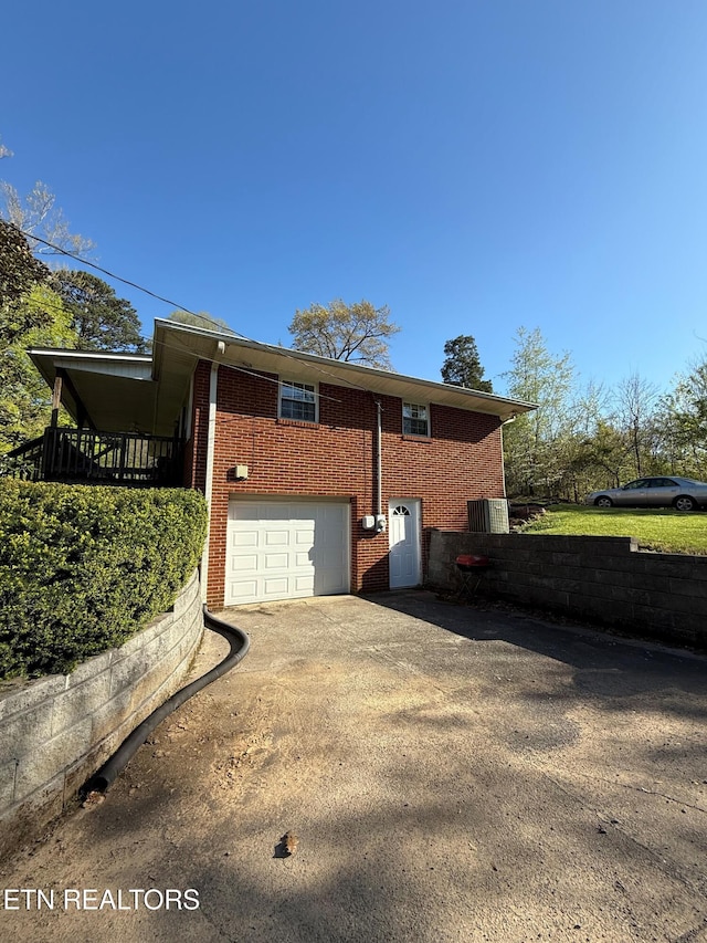 view of property exterior featuring a garage, aphalt driveway, brick siding, and central AC