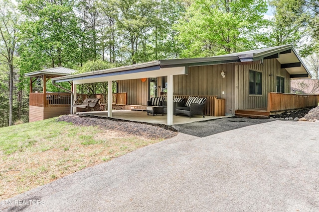 view of front of property featuring a patio, a wooden deck, an outdoor hangout area, and board and batten siding