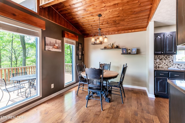 dining area with baseboards, wood finished floors, a chandelier, and vaulted ceiling