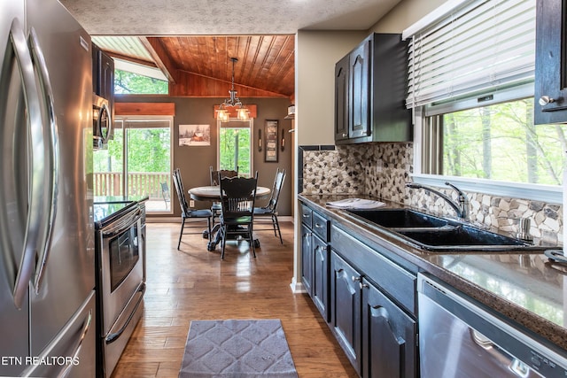 kitchen featuring wooden ceiling, appliances with stainless steel finishes, vaulted ceiling, dark countertops, and a sink
