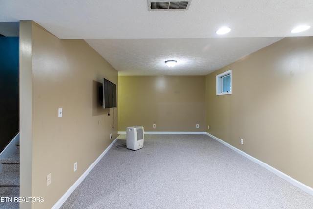 finished below grade area featuring a textured ceiling, visible vents, baseboards, carpet floors, and recessed lighting