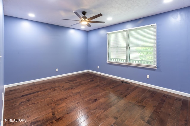 spare room with dark wood-style floors, visible vents, ceiling fan, and baseboards