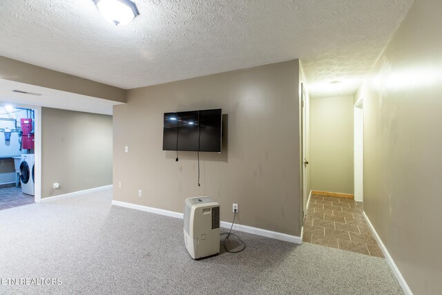 unfurnished living room with baseboards, washer / clothes dryer, a textured ceiling, and carpet floors