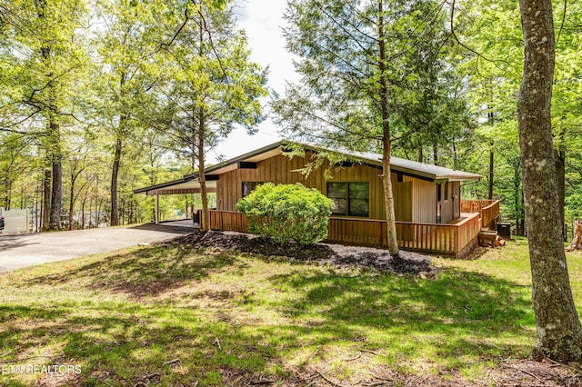 view of side of home with a lawn, driveway, board and batten siding, and a carport