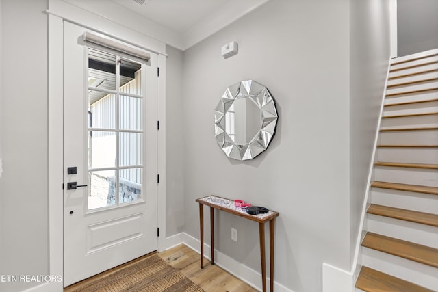 doorway to outside with baseboards, light wood finished floors, and stairs