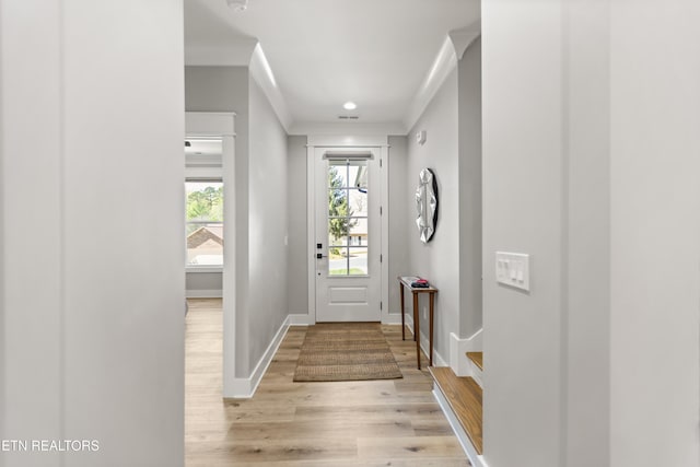 entryway with light wood-style flooring, baseboards, and ornamental molding
