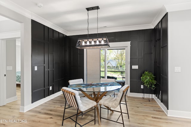 dining space featuring light wood-style flooring, baseboards, and ornamental molding