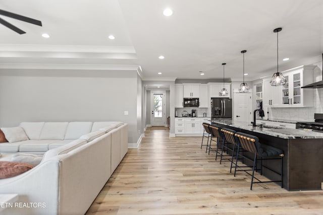 kitchen featuring a sink, black appliances, a kitchen bar, ornamental molding, and recessed lighting