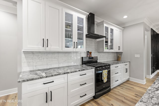 kitchen with light stone countertops, baseboards, gas stove, and wall chimney range hood