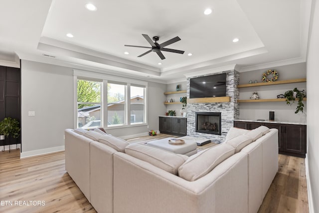 living room with light wood finished floors, a ceiling fan, recessed lighting, and a raised ceiling