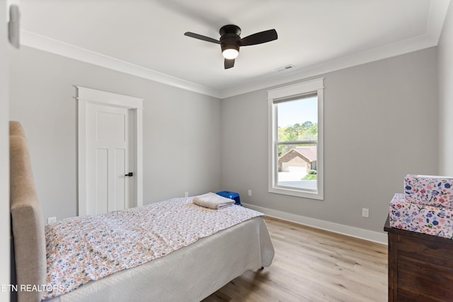 bedroom featuring light wood-style flooring, baseboards, visible vents, a ceiling fan, and ornamental molding