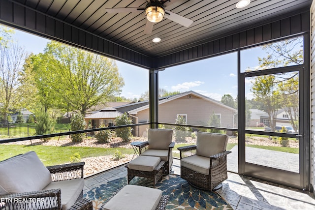 sunroom with a residential view, an outdoor living space, and a ceiling fan