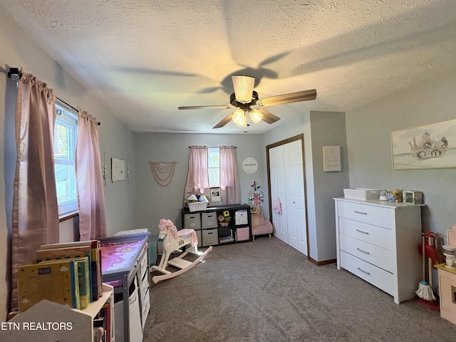 interior space featuring a ceiling fan, carpet floors, a textured ceiling, and a healthy amount of sunlight