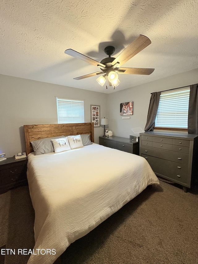bedroom featuring dark colored carpet, a textured ceiling, and ceiling fan