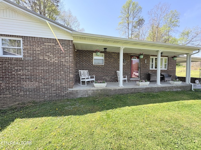 back of property featuring brick siding and a yard