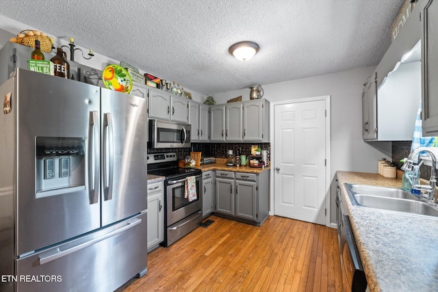 12903 Georgetown Village Ln, Georgetown, TN 37336 - kitchen featuring appliances with stainless steel finishes, gray cabinetry, light wood finished floors, a sink, and decorative backsplash
