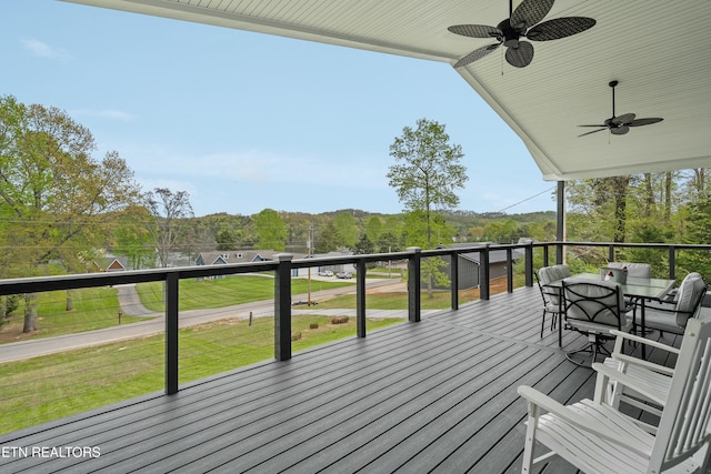wooden deck featuring a lawn, a ceiling fan, and outdoor dining area